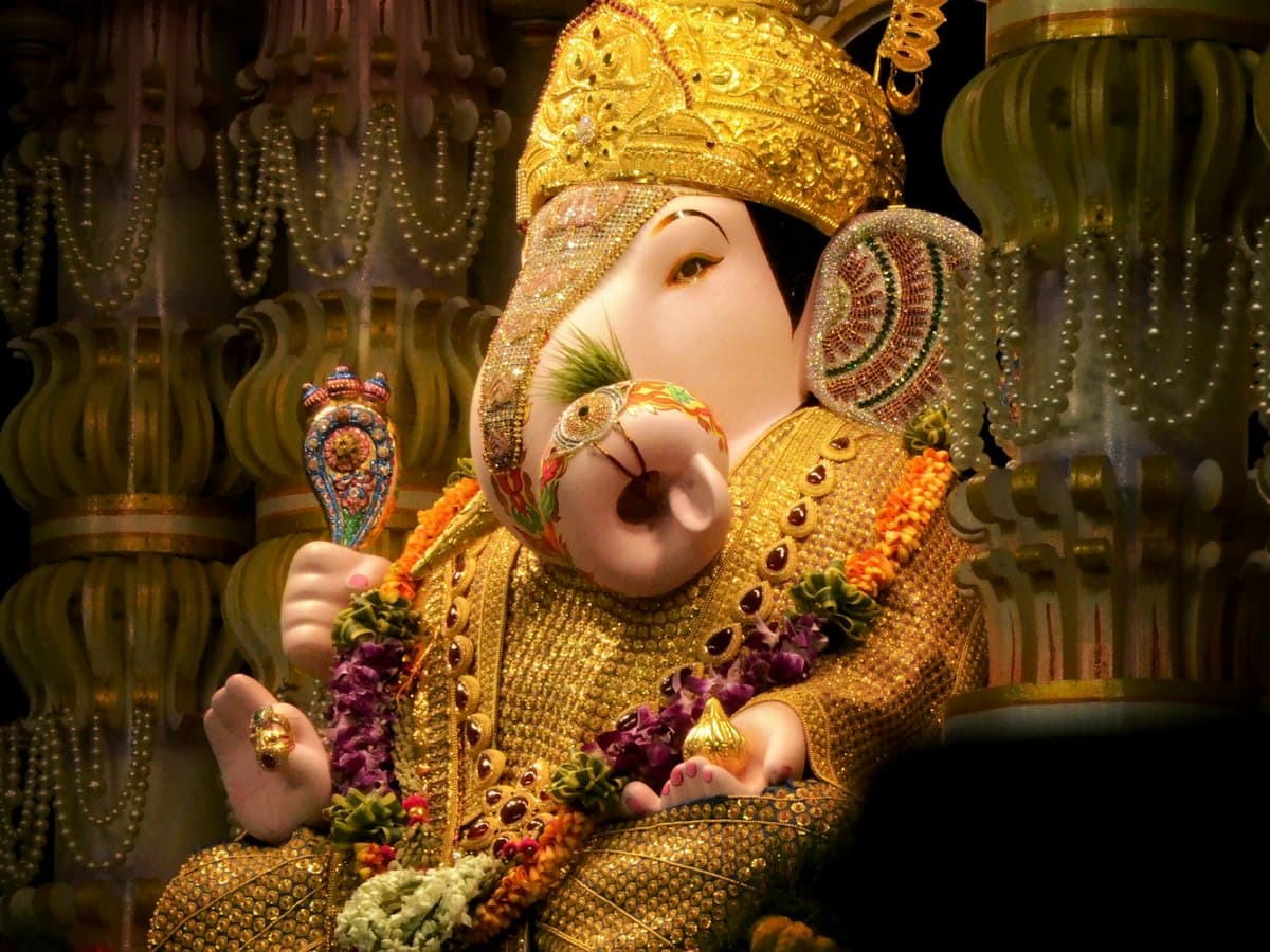 A golden Ganesha statue adorned with flowers at the Dagdusheth Halwai Ganpati temple, Pune