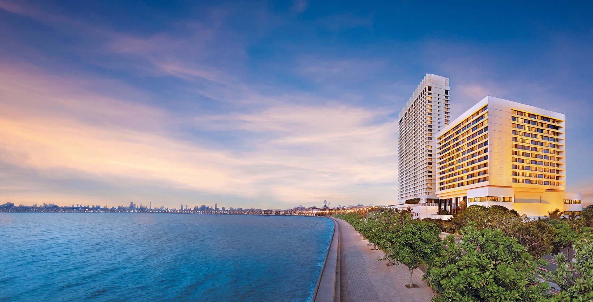 The Oberoi, Mumbai tower beside the Marine Drive promenade and the Arabian Sea at dusk