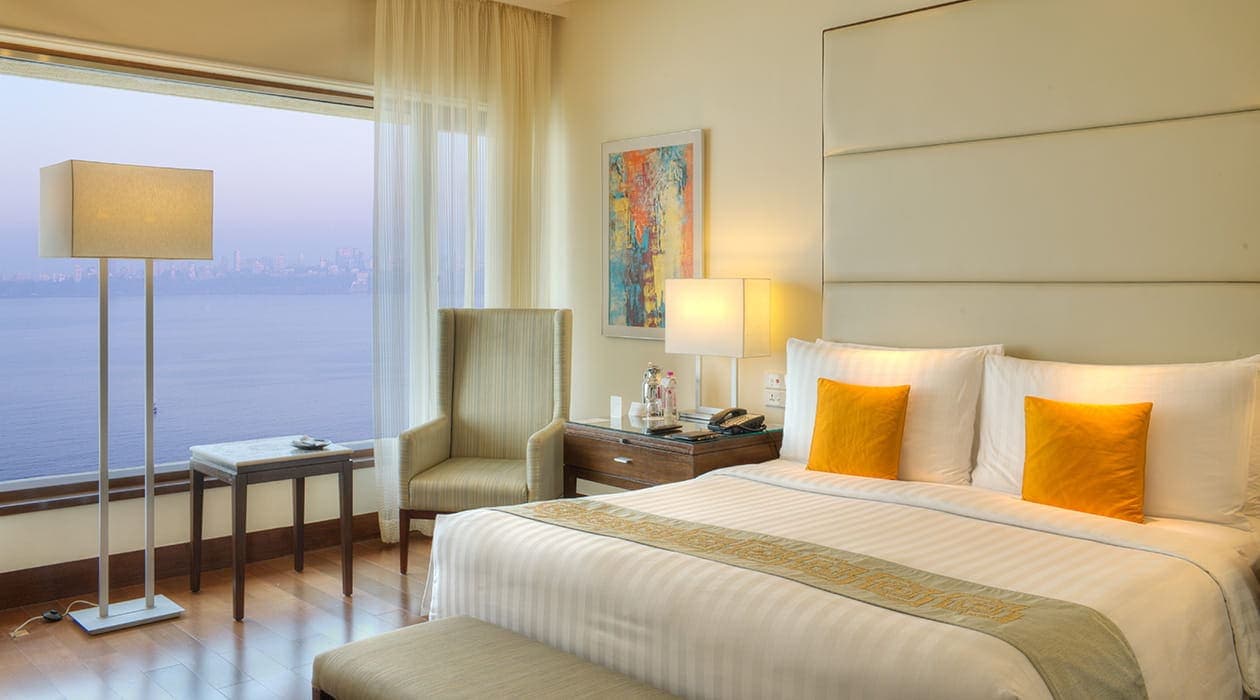 Bay view room with king bed, armchair and floor-to-ceiling window over the sea at The Oberoi, Mumbai