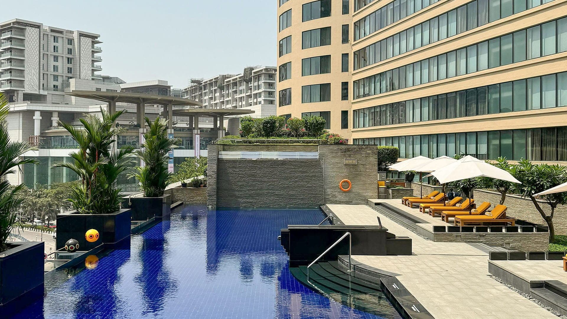 Blue-tiled pool with sun loungers and a stone water wall at Trident, Bandra Kurla
