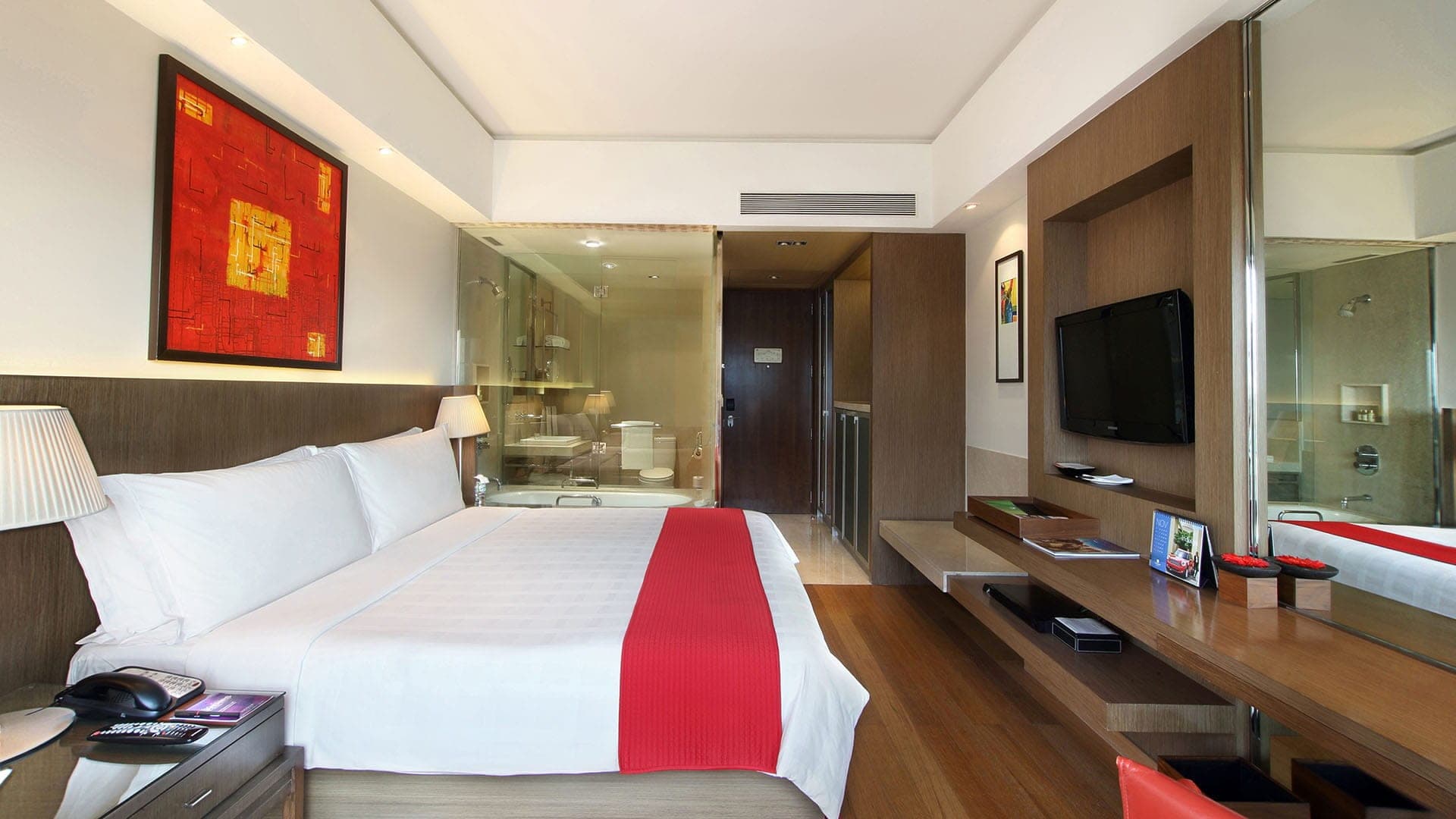 Deluxe Room with a king bed, red bed runner and glass-fronted bathroom at Trident, Bandra Kurla