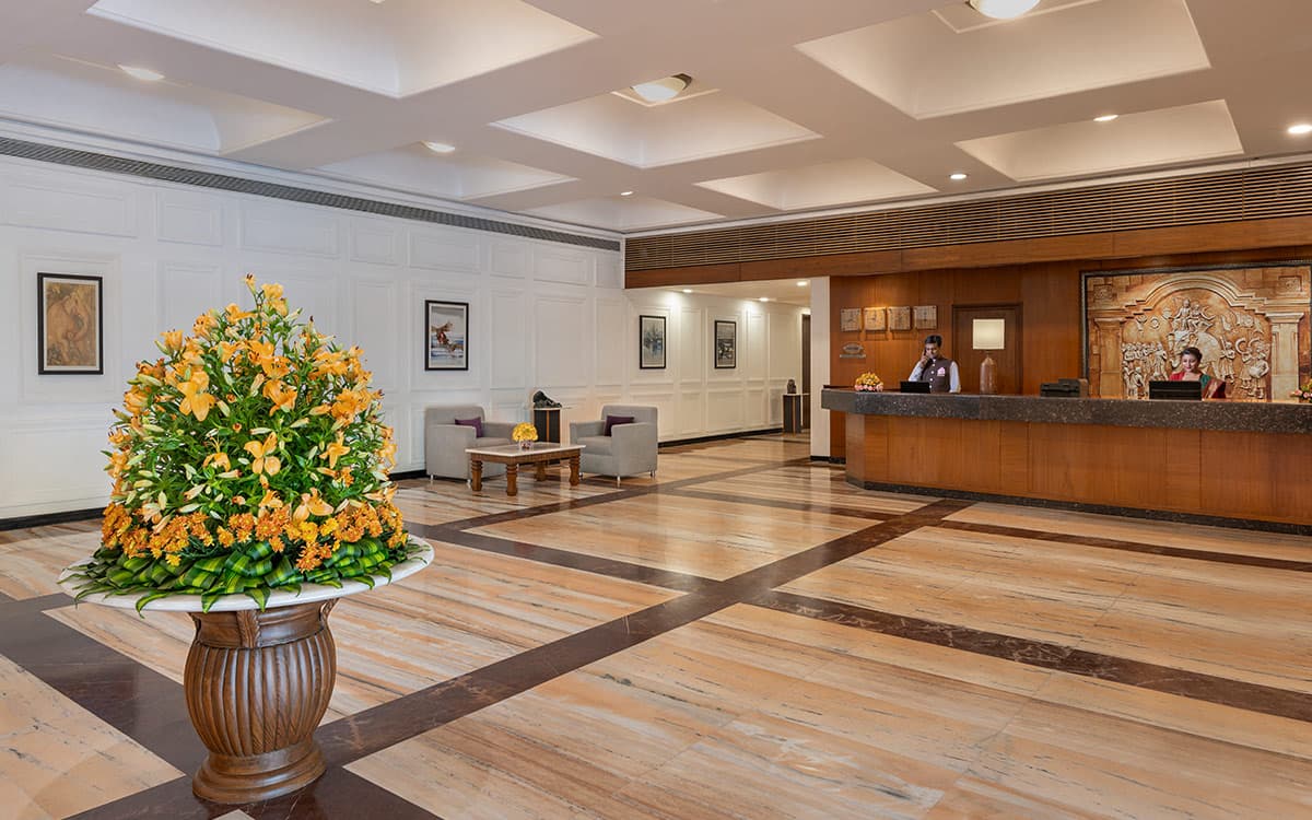 Lobby and reception desk with a floral arrangement at Welcomhotel Rama International, Aurangabad