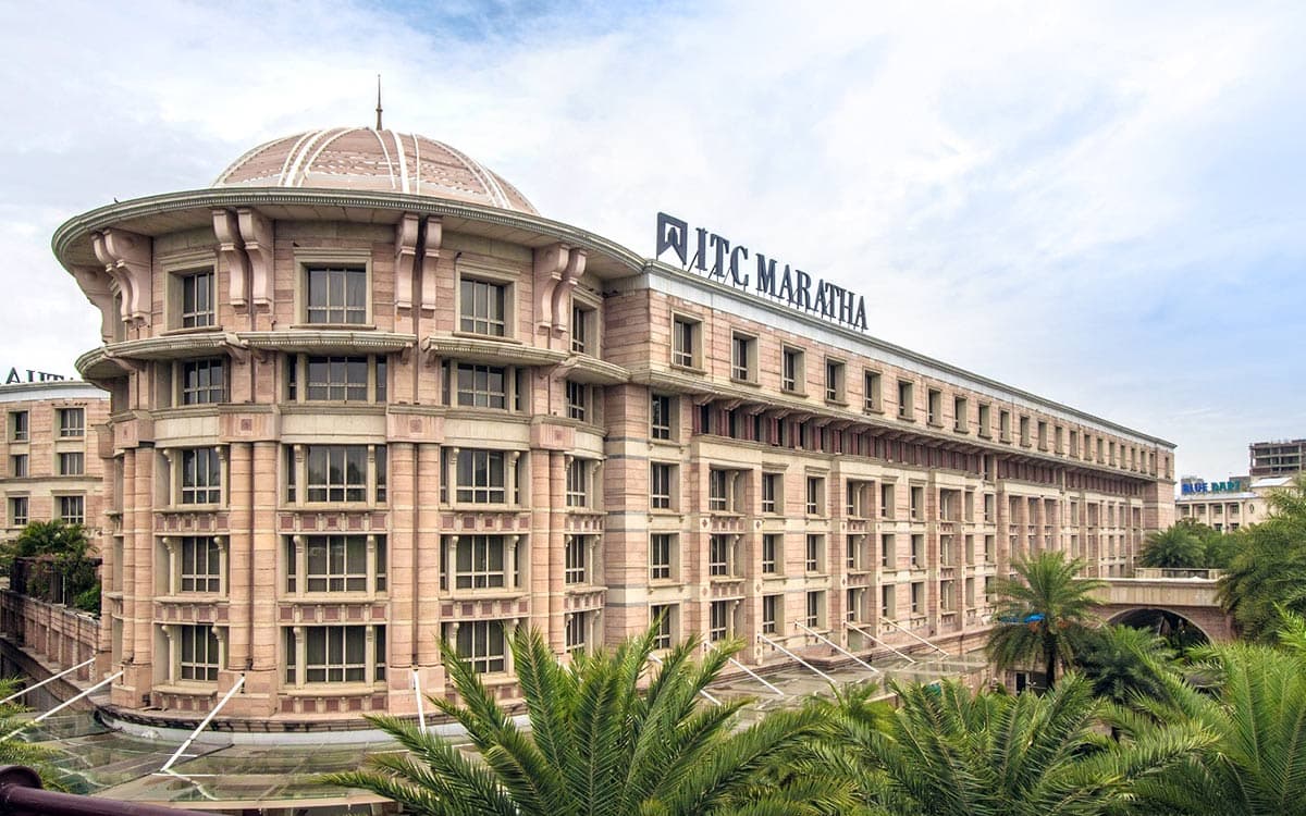 The domed, sandstone-toned facade of ITC Maratha in Mumbai with palms in the foreground