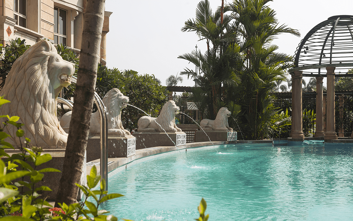 Curved pool with stone lion fountains and palms at ITC Maratha, Mumbai