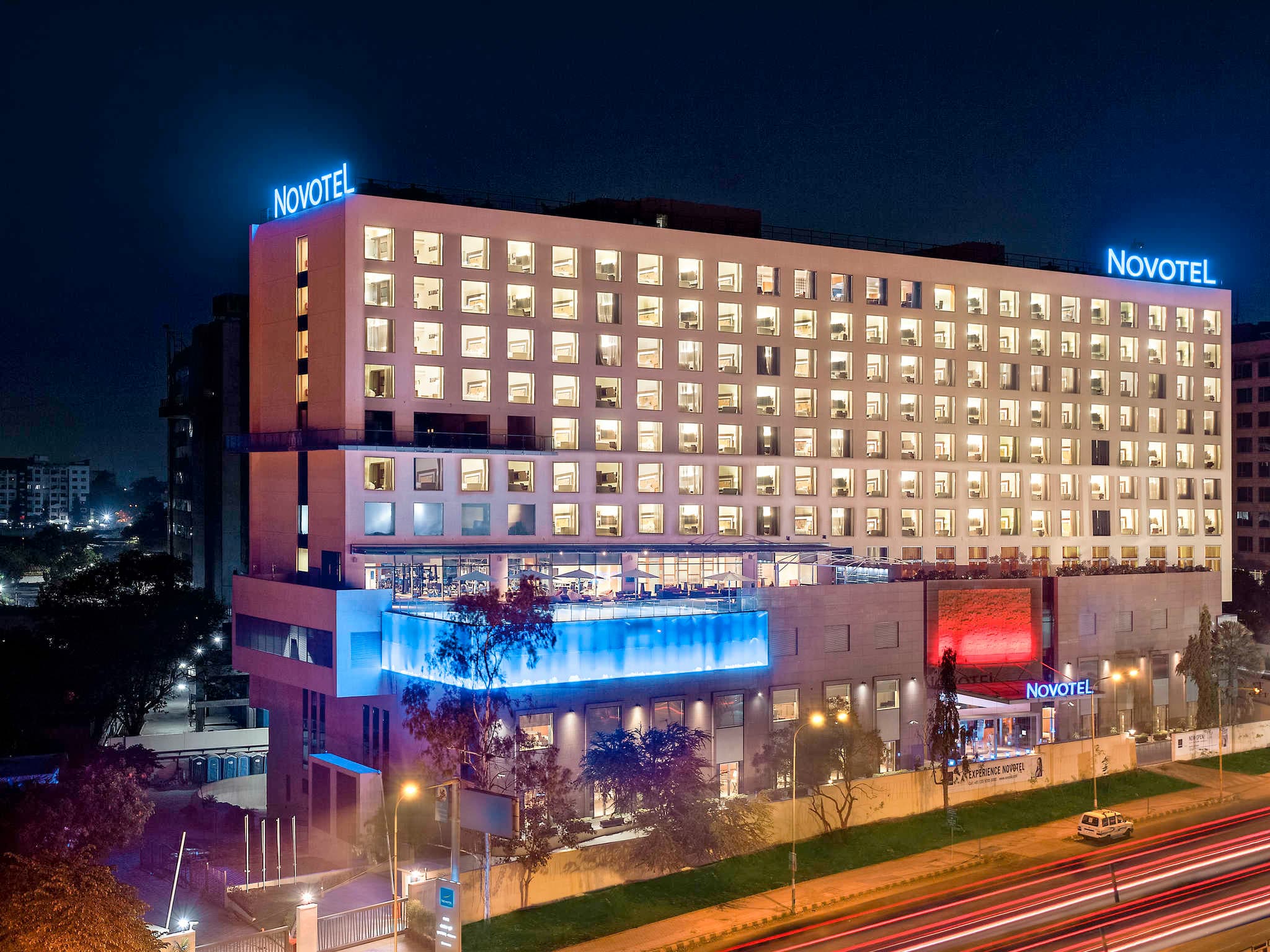 Novotel Pune Nagar Road facade lit at night with the pool terrace below