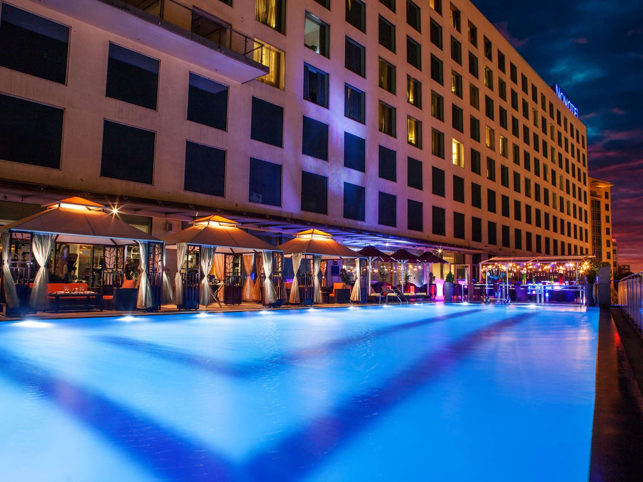 Rooftop pool and cabanas at dusk beside the Novotel Pune Nagar Road tower