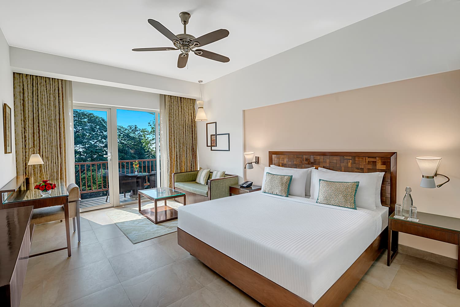 Deluxe King room with a balcony, sofa and wooden headboard at Fariyas Resort Lonavala