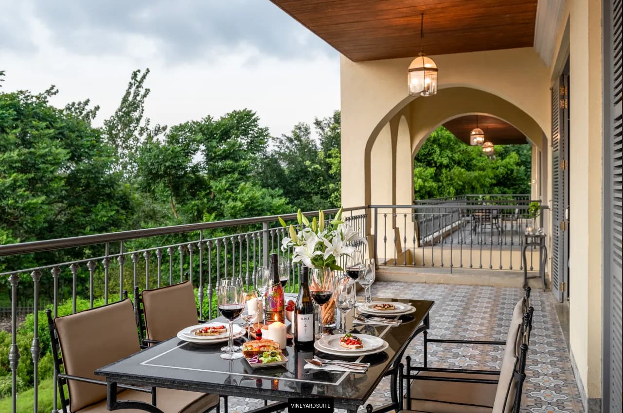 Terrace dinner table laid with wine glasses under an arched veranda at The Source at Sula