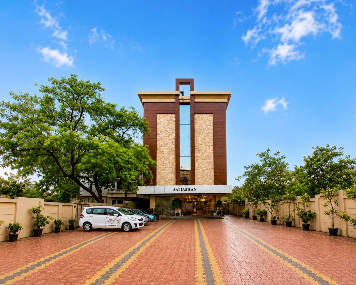Hotel Sai Jashan Shirdi's facade and brick forecourt under a blue sky