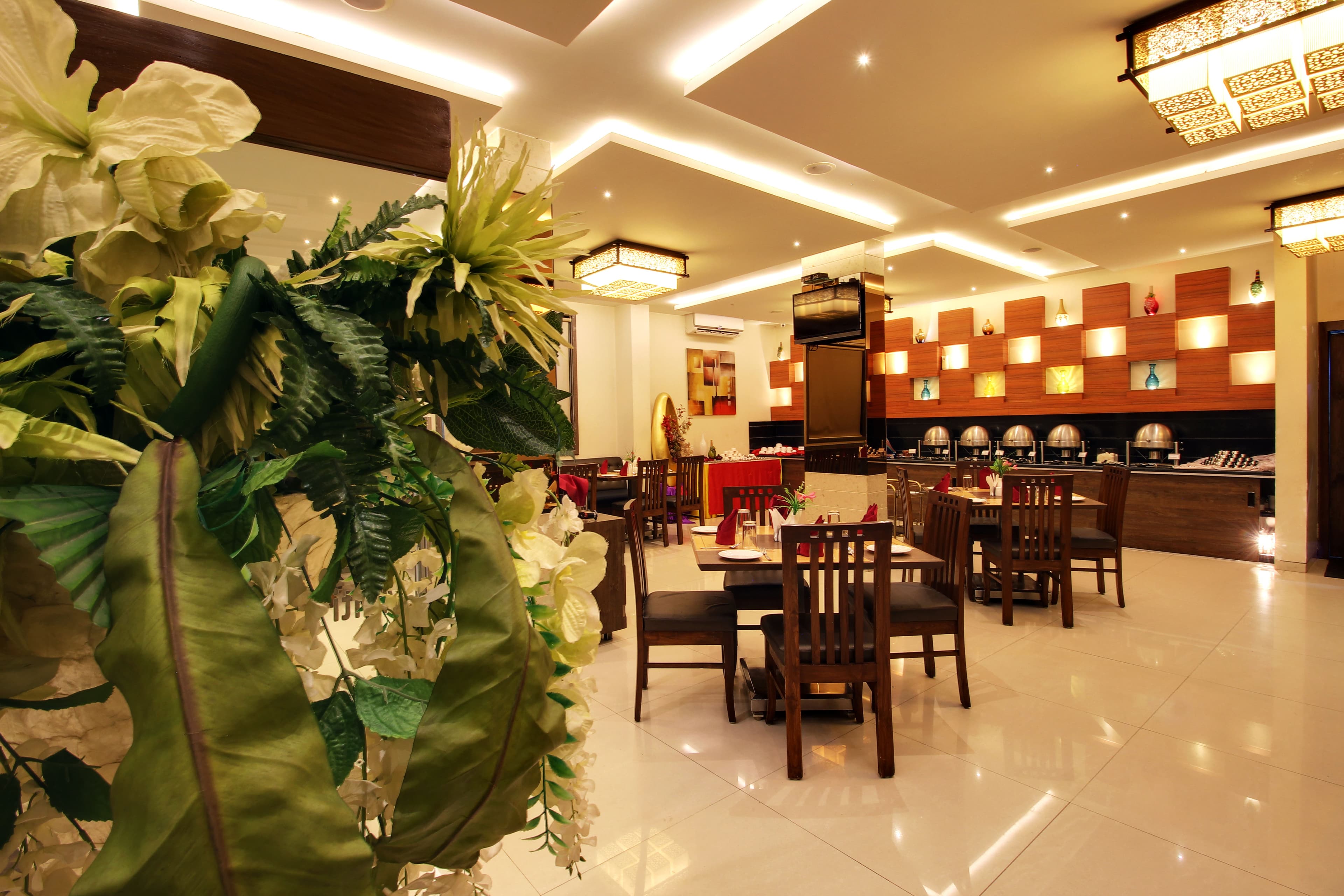 Basil Leaves restaurant at Hotel Sai Jashan, with wooden tables and a warm lit buffet wall