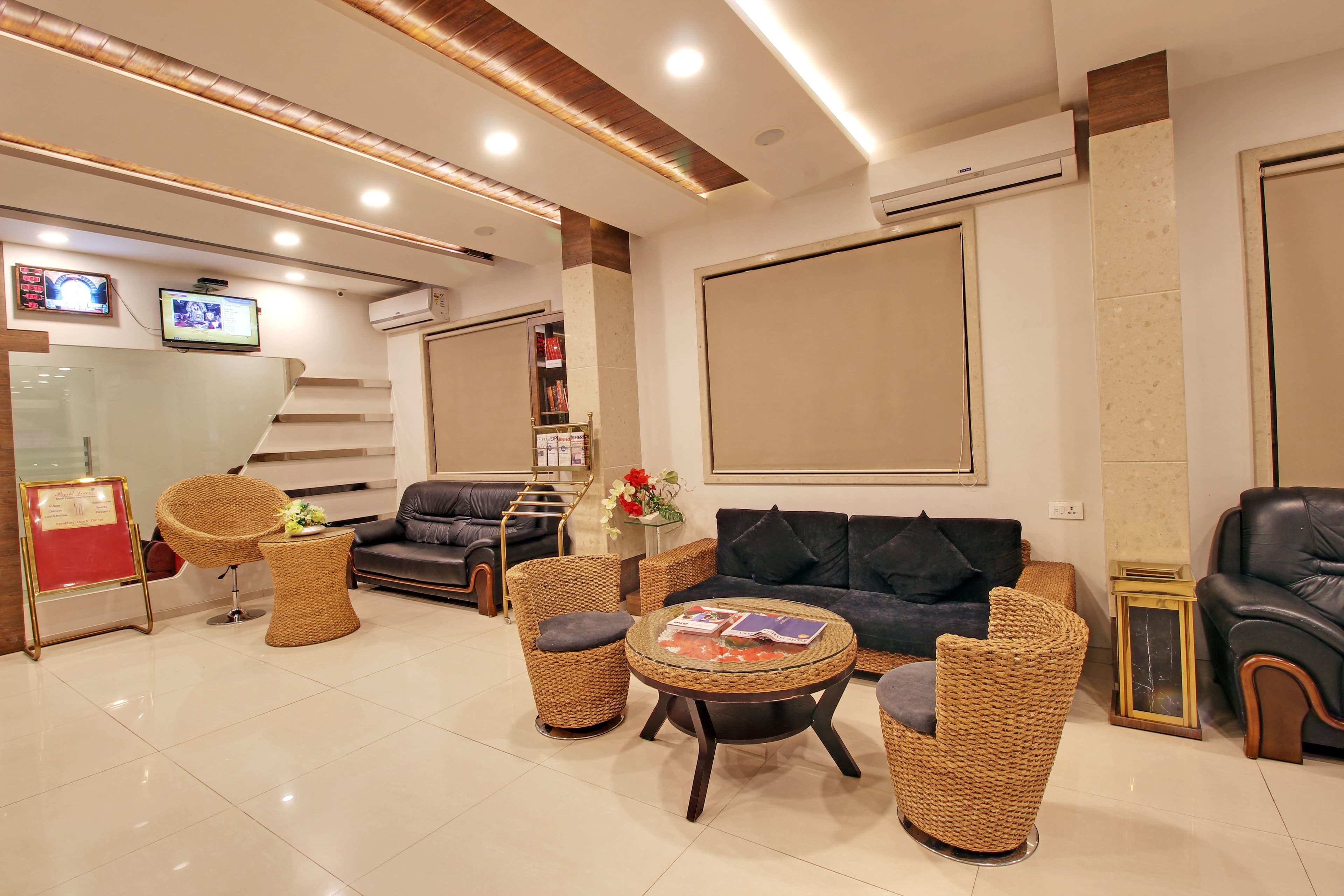 Ground-floor lounge at Hotel Sai Jashan with sofas and wicker armchairs
