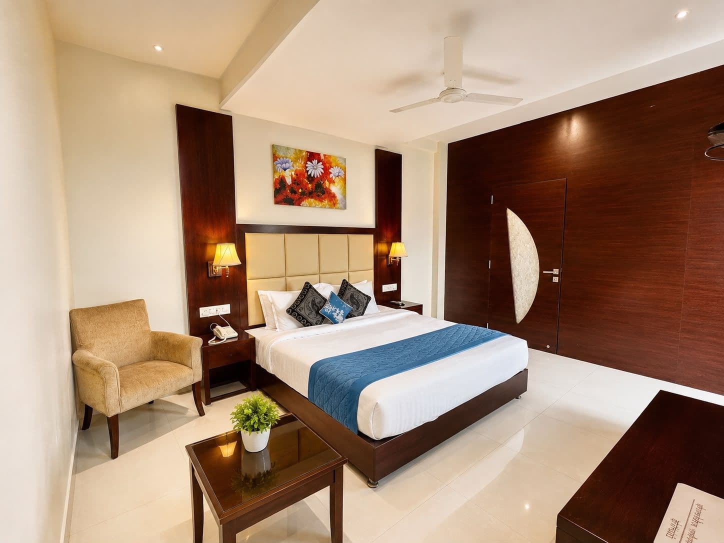 Suite room with a king bed, armchair and wooden wardrobe wall at Hotel Sai Jashan