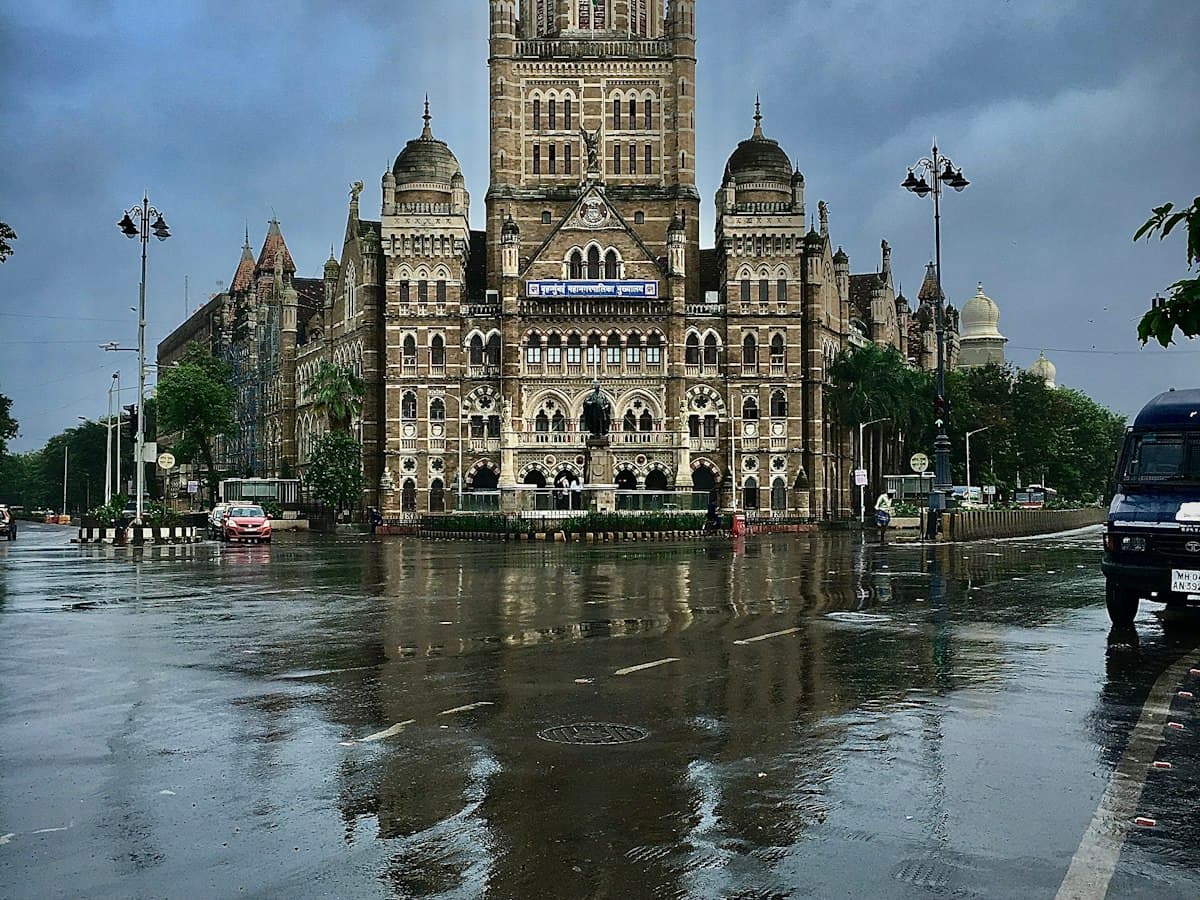 Brihanmumbai Municipal Corporation building reflected on a rain-slicked street opposite CSMT in Mumbai's Fort district