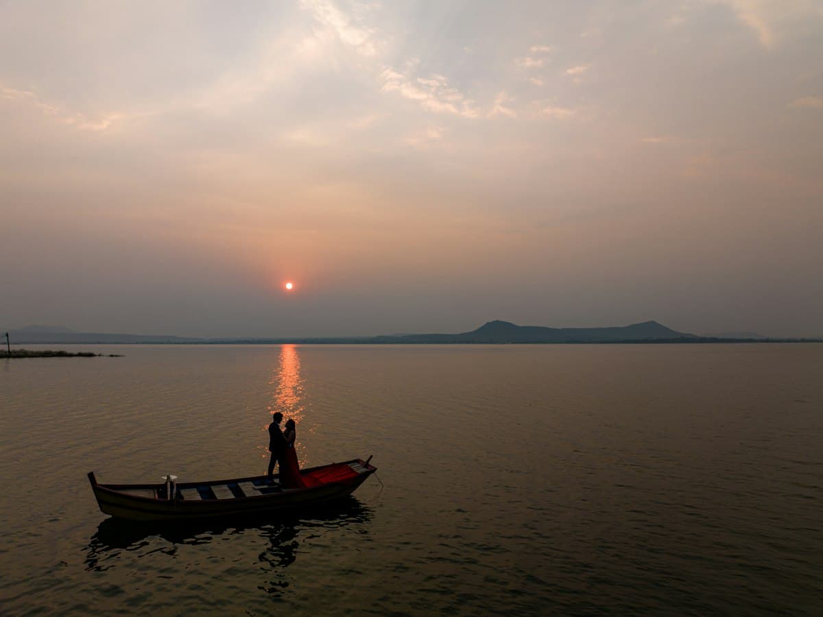 Two people in a boat on the still backwater at Sula Wine Yards, Nashik, at sunrise