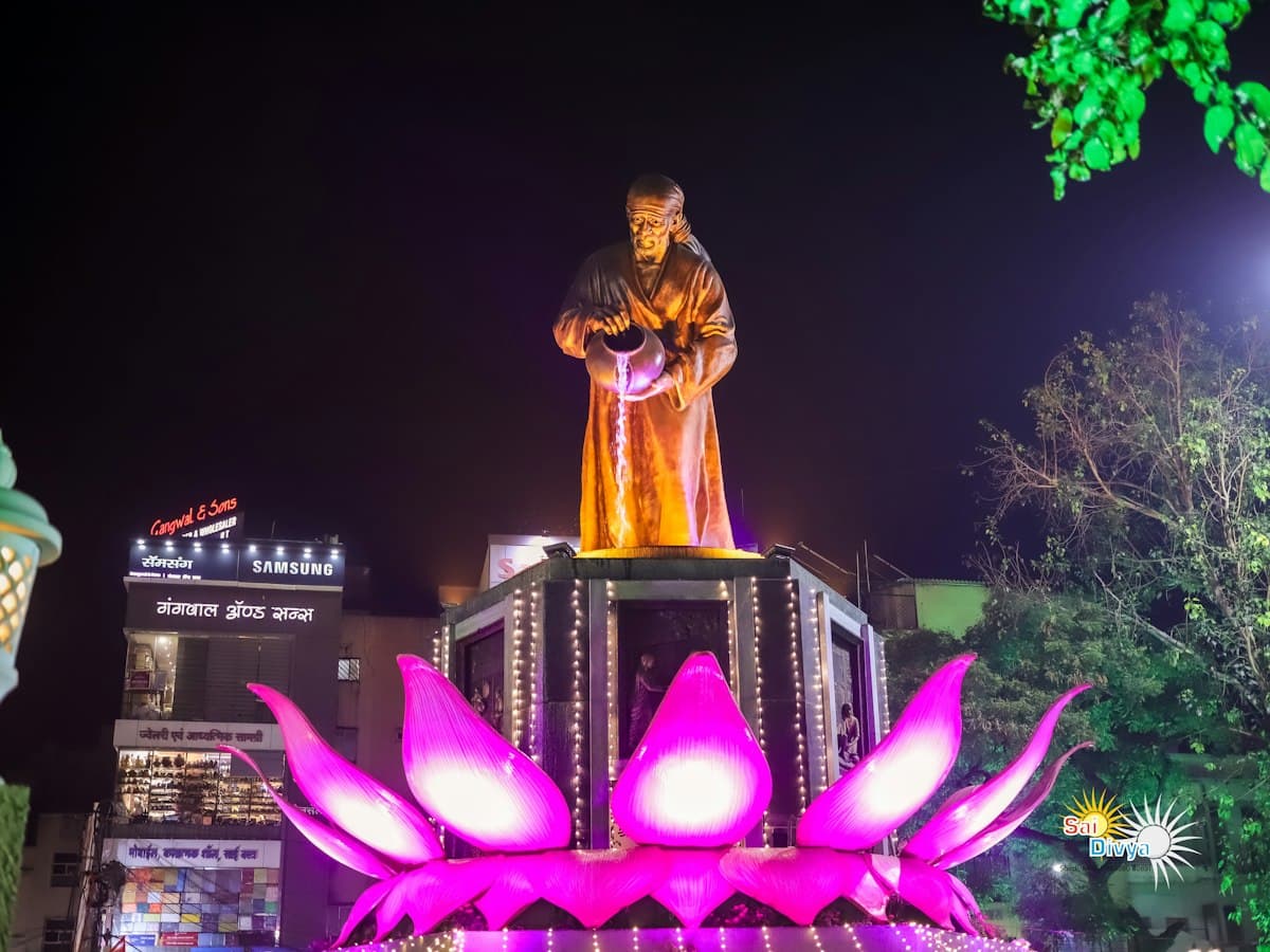 A statue of a standing figure beneath the moon at night in Shirdi, Maharashtra