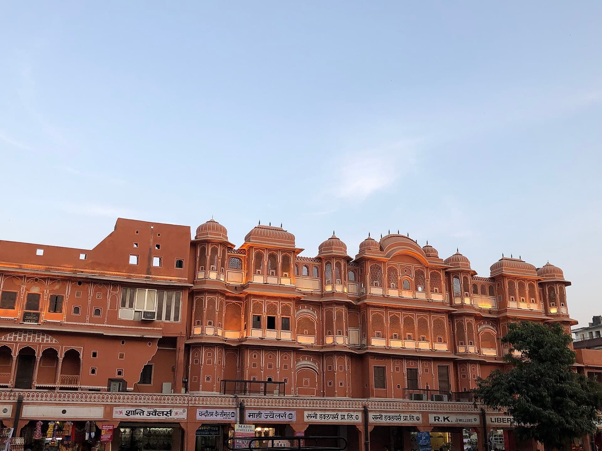 Pink sandstone shopfronts with latticed balconies in a Jaipur bazaar at dusk