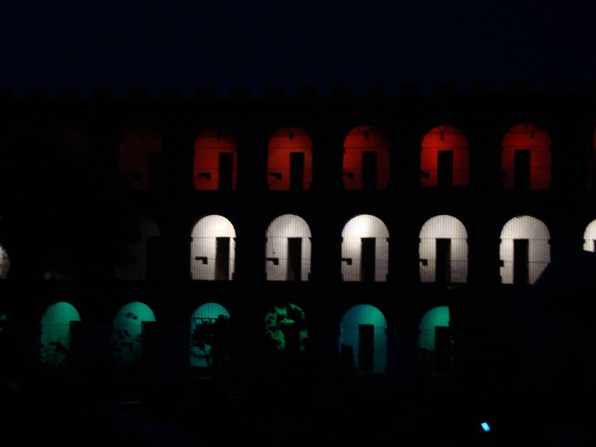 Cell windows lit in white and orange during the light and sound show at Cellular Jail