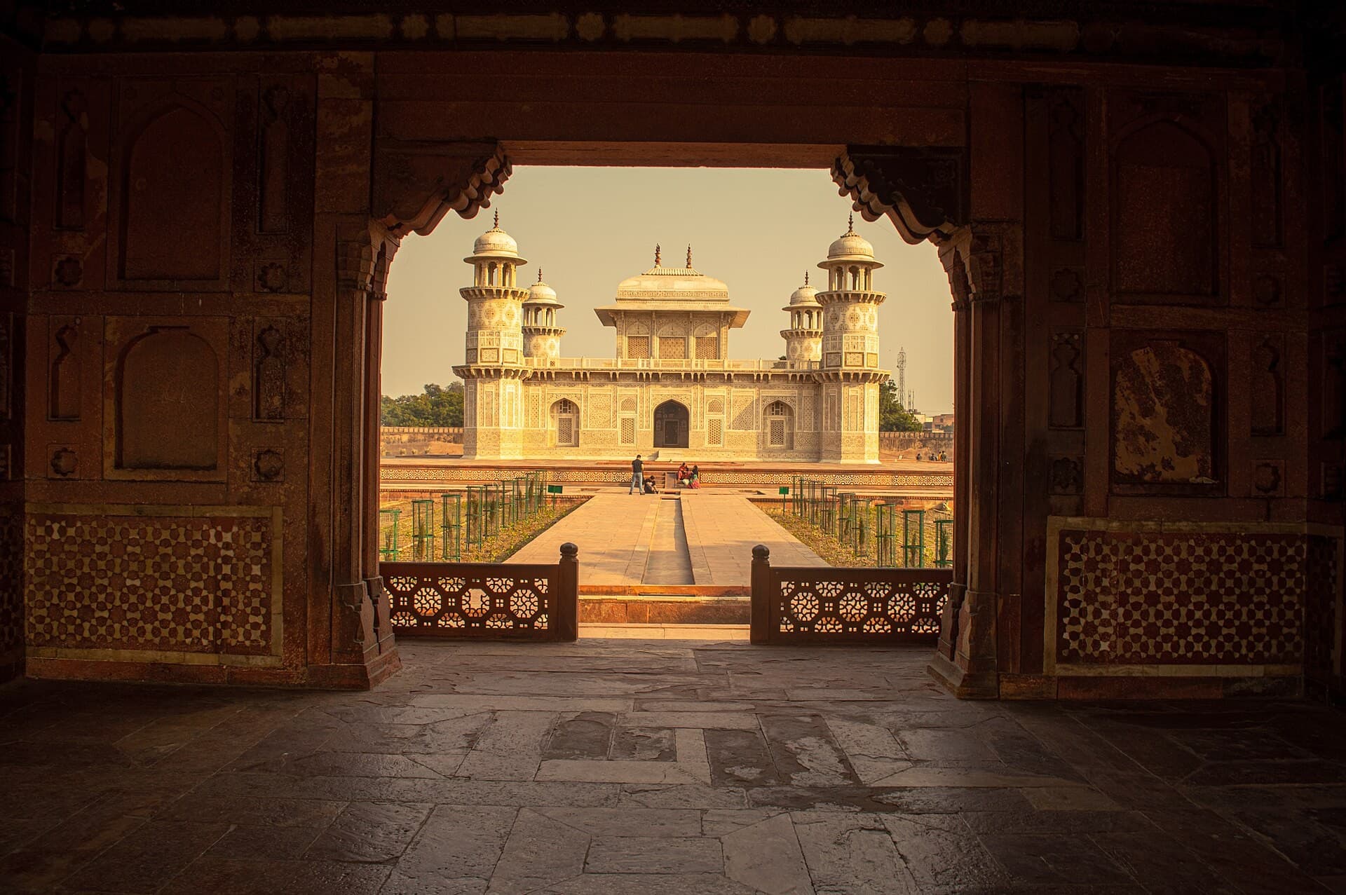 The tomb of Itimad-ud-Daulah seen through a carved stone gateway in warm light